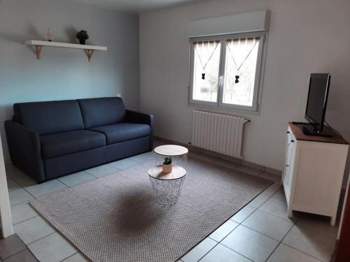 ein Wohnzimmer mit einem Sofa und einem Tisch in der Unterkunft L'écrin de verdure à 25 minutes du Puy du Fou in Cerizay