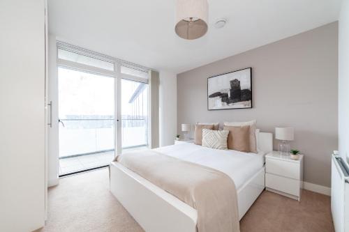 a white bedroom with a large bed and a window at The Thames Collection in London