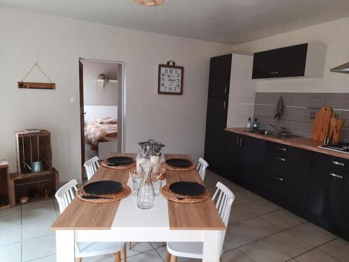 eine Küche mit einem Holztisch mit weißen Stühlen und einem weißen sidx sidx sidx. in der Unterkunft L'écrin de verdure à 25 minutes du Puy du Fou in Cerizay
