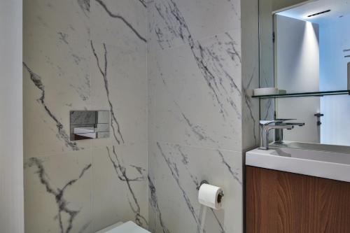 La salle de bains est pourvue d'un lavabo et d'un mur en marbre. dans l'établissement Sublime Appartement Promenade des Anglais (1), à Nice