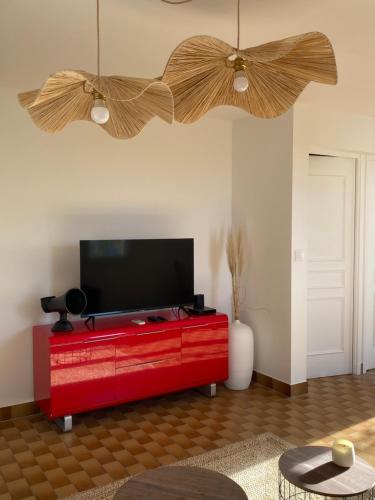 a living room with a red entertainment center with a flat screen tv at Appartement avec vue sur château et piscine privée in Hyères