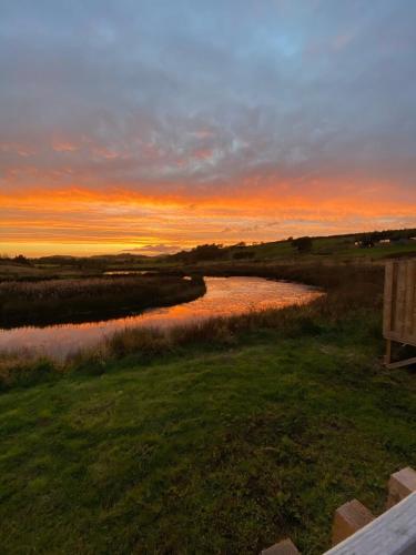a view of a river at sunset with a bench at Pond View Pod 2 with Private Hot Tub - Fife - Loch Leven - Lomond Hills in Kelty