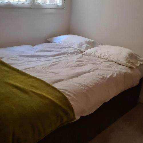 1 cama no hecha con sábanas blancas y manta amarilla en H&B Apart, en Barcelona
