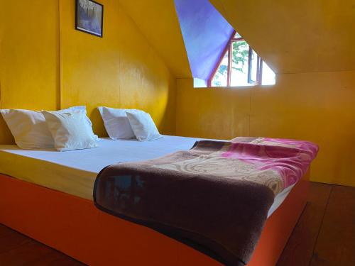 a bedroom with a large bed with a window at Castaway Offbeat Stay in Manāli