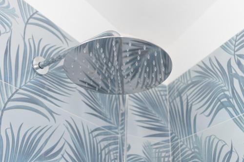 a chrome floor lamp with a tropical leaf wallpaper at Sole e Girasoli in Molfetta