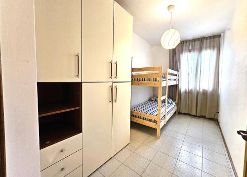 una cucina con armadietti bianchi e un letto a castello di Matteo's Apartments Cecina Mare a Cecina