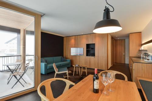 a kitchen and living room with a table with a wine bottle at Fuxbau in Stuben am Arlberg