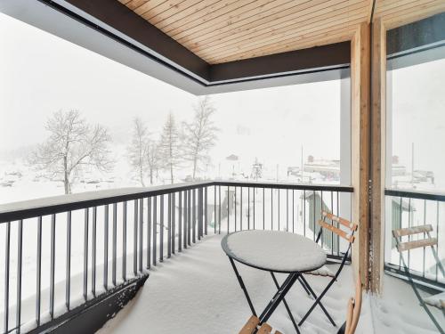 a table and chair on a balcony with snow covered trees at Fuxbau in Stuben am Arlberg