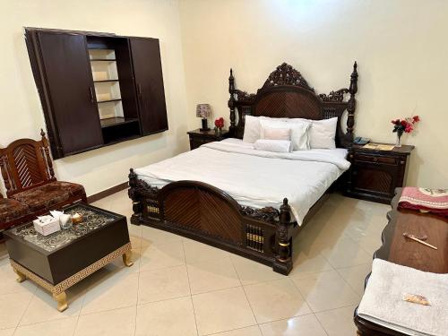 a bedroom with a large wooden bed and a chair at Hotel Shelton Palace in Multan