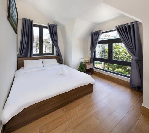 a bedroom with a large bed and large windows at Nhà Giáng Sinh Trên Đồi Villa in Da Lat