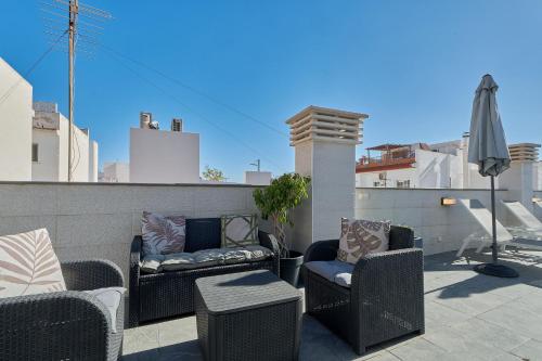 a patio with wicker chairs and a table and an umbrella at Solaga - Nueva 22 in Nerja