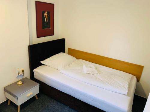 1 dormitorio con 1 cama con sábanas blancas y mesa en Hotel Slovan, en Žilina