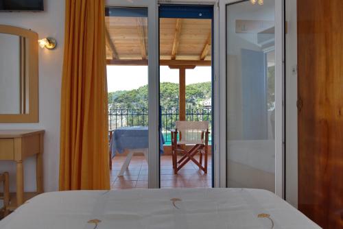 a bedroom with a bed and a view of a balcony at Kavos Hotel in Patitiri