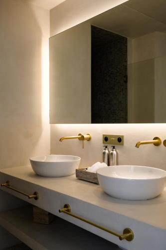 a bathroom with two white sinks and a mirror at Le Couvent des Minimes, un Hôtel & Spa L'Occitane en Provence in Mane