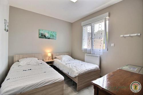 1 dormitorio con 2 camas, mesa y ventana en Les hortensias en Louannec