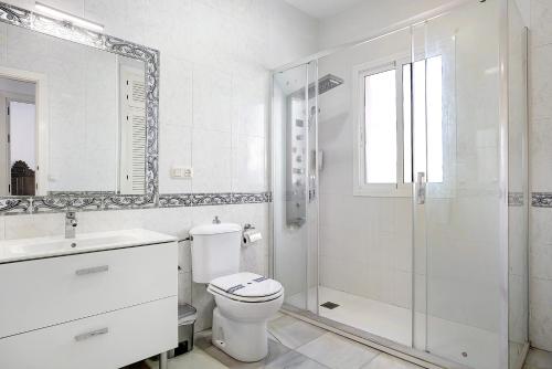 uma casa de banho branca com um WC e um chuveiro em Chalet con Piscina y Barbacoa 4 d em Chiclana de la Frontera