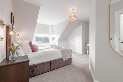 a white bedroom with a large bed and a mirror at Skye Sands - 11 Alexandra Penthouse - St Andrews in St Andrews