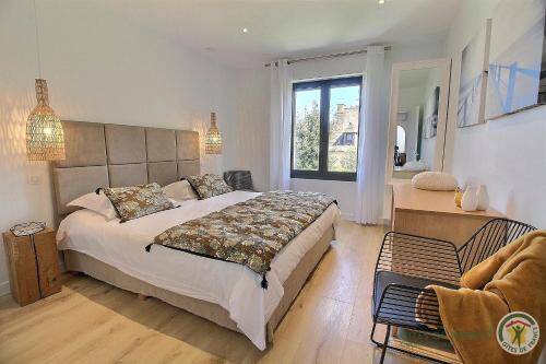 Un dormitorio con una cama grande y una ventana en Les oliviers, en Perros-Guirec