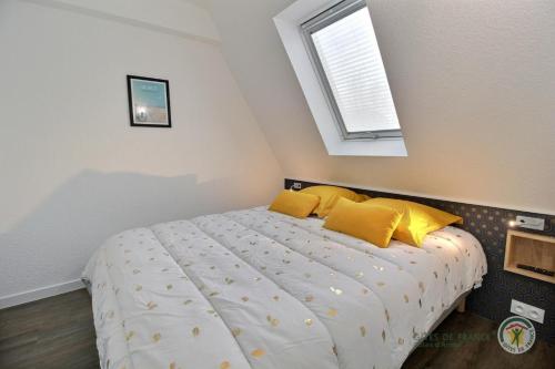 - une chambre avec un lit doté d'oreillers jaunes et d'une fenêtre dans l'établissement La terrasse sur le golf, à Pleumeur-Bodou