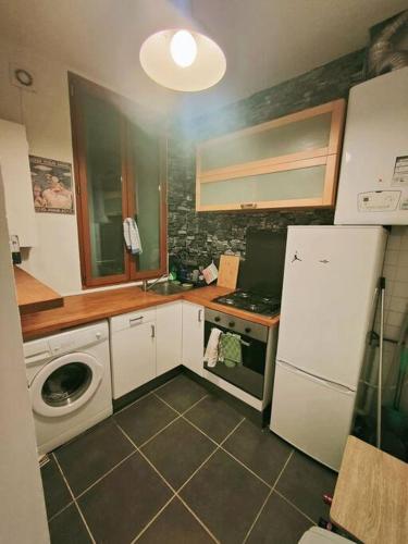 Il comprend une cuisine équipée d'un réfrigérateur blanc et d'un lave-linge. dans l'établissement Charmant deux pièces - Tout Confort - écusson, à Montpellier