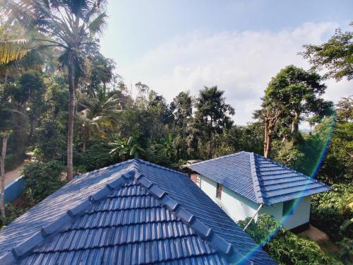 ein blaues Dach eines Hauses mit Bäumen im Hintergrund in der Unterkunft Sri Sai Nature Stay in Madikeri