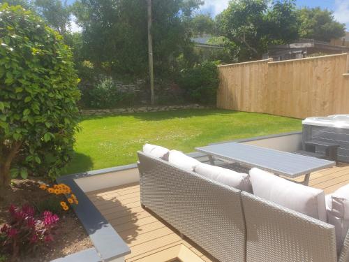 a patio with white couches and a grill in a yard at Modern open plan house, sea views and hot tub in Falmouth