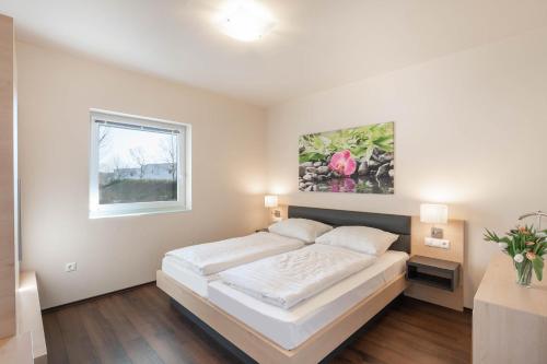 ein weißes Schlafzimmer mit einem Bett und einem Fenster in der Unterkunft Appartements Thermen-Golfresort Pannonia in Zsira