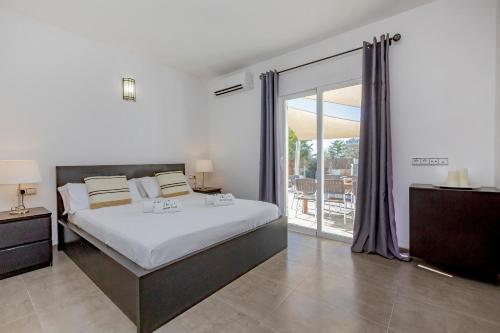 a bedroom with a large bed and a balcony at Villa near San Antonio sleeps 10 in Ses Paisses