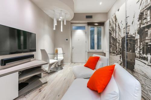 un soggiorno con divano bianco e cuscini arancioni di [DUOMO 14 min] Orange Milano M3 a Milano