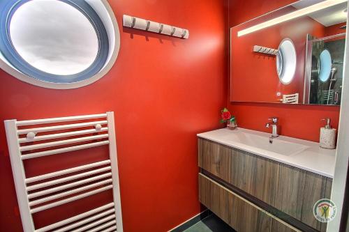 ein rotes Badezimmer mit einem Waschbecken und einem Spiegel in der Unterkunft La roche mignonne in Trébeurden