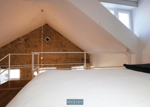 a white bed in a room with a loft at MyStay - D Maria Apartments in Vila Nova de Famalicão