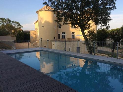 une piscine avec une maison en arrière-plan dans l'établissement Appartement 2ème étage 4 personnes dans Château avec piscine collective, à Lussan