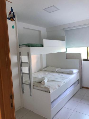 a white bunk bed with a ladder in a room at Muro Alto Flat Nui Supreme in Porto De Galinhas