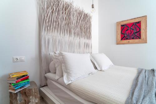 a bedroom with a white bed and a painting on the wall at F Fine Suites - Adults Only in Líndos
