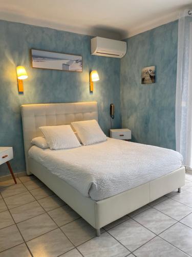 a bedroom with a white bed and blue walls at Logis Hôtel Le Clement V in Roquemaure