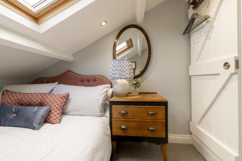 a bedroom with a bed with a mirror and a dresser at Kitten Cottage in West Witton