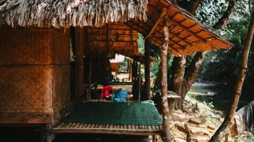 une cabane avec une table verte et un toit de paille dans l'établissement สวนบุศรา ลานกางเต็นท์วิถีเกษตร, à Ban Bok Fai