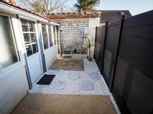 a patio with a door and a chair next to a building at Le Studio du Marais in Aux Marais