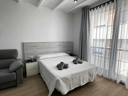 a bedroom with a bed and a chair and windows at A H Rentals Picasso apartamento in Vinaròs
