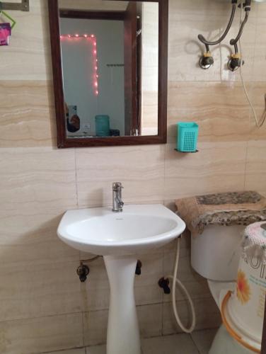 uma casa de banho com um lavatório, um espelho e um WC. em Home Stay 1 em Noida