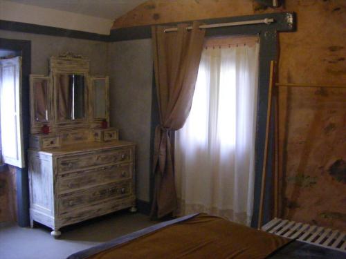 1 dormitorio con tocador, espejo y ventana en LES ANGES, en Covelo