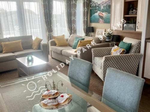 uma sala de estar com um sofá e uma mesa em Marlow - Gold 2 bed with veranda and parking at Seal Bay Resort em Selsey