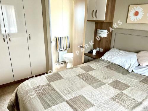 um quarto com uma cama e um WC. em Marlow - Gold 2 bed with veranda and parking at Seal Bay Resort em Selsey