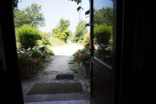 an open door to a garden path with flowers at Agriturismo Montevecchio Isolani in Monte San Pietro