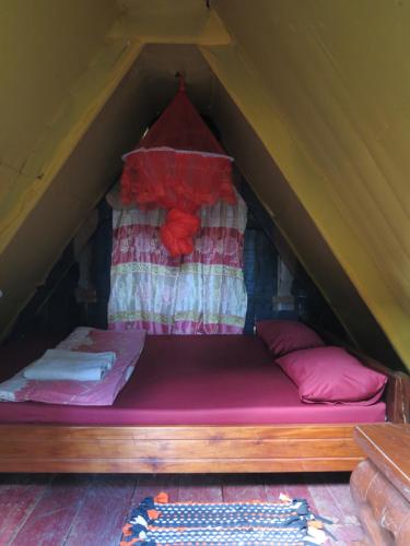a bed in a tent with pink sheets and pillows at Ratanakiri Homestay & Jungle Trek in Banlung