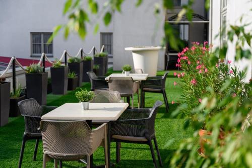 a row of tables and chairs on a lawn with plants at Mercure Szekesfehervar Magyar Kiraly in Székesfehérvár