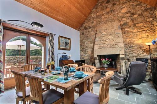 - un salon avec une table, des chaises et un mur en pierre dans l'établissement Maison bleue, à Plougrescant