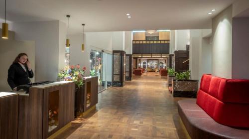 a woman standing at a counter in a lobby at Clayton Hotel Amsterdam American in Amsterdam