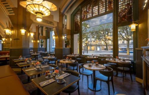 a restaurant with tables and chairs and a large window at Clayton Hotel Amsterdam American in Amsterdam