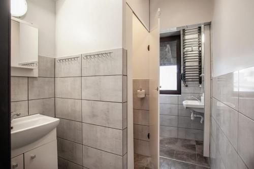 ein weißes Badezimmer mit einem Waschbecken und einem Spiegel in der Unterkunft Pokoje na Wilkońskich, Swarzędz in Swarzędz
